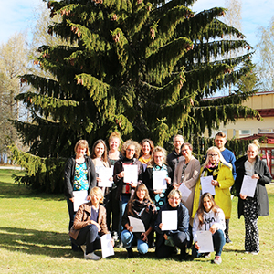 Kuvassa kansainvälisen digihankkeen osallistujat ryhmäkuvassa Ähtärin Tuomarniemen pihakuusen edessä.